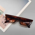 Detailed view of tortoiseshell rectangle sunglasses with brown lenses on a magazine background - Leopard Print