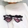 Vue détaillée de lunettes de soleil cœur noir avec verres dégradés violets sur magazine - Noir