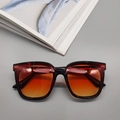 Close-up of stylish square sunglasses featuring orange gradient lenses and metal rivets - Black Frame Orange Gradient