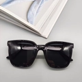 Detail of square black oversized sunglasses with silver accents on light gray background - Black Frame Full Grey