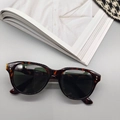 Close-up of caramel tortoise shell sunglasses with dark lenses and metallic rivets - Leopard Green Lens