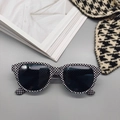 Detail of square checkered sunglasses with dark lenses and metallic rivets on gray background - Black White Grid