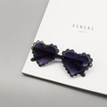 Detail einer herzförmigen Glitzersonnenbrille mit Wellenschliff und lila Verlaufsgläsern - Grau