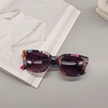 Square floral print sunglasses with purple gradient lenses on a minimalist desk - Anagallis