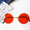 Detail view of round vintage kids sunglasses with red lenses and gold metal frames - Red