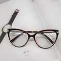 Cat eye glasses in tortoise shell pattern with gold metal temples on a white magazine - Transparent Dark Brown