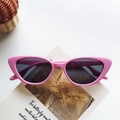Pink triangular cat-eye kids sunglasses with grey UV400 lenses on a vintage book - Pink