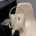 Cremeweiße Bucket Bag aus Leder mit Falten und Goldschnalle auf weißem Stuhl - Cremeweiß