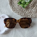 Detailed close-up of classic tortoiseshell sunglasses with amber frames and brown lenses - Tortoise Brown