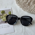 Lunettes de soleil rondes surdimensionnées noires avec verres gris sur un tapis blanc - Noir et Gris