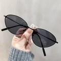 Primo piano di occhiali da sole cat-eye in metallo sottile con lenti scure tenuti in mano - Grigio Scuro