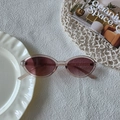 Retro oval sunglasses with translucent pink frame and deep red lenses on table - Champagne