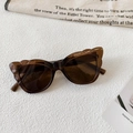 Close-up of dark brown cat-eye sunglasses with detailed frame specs on inner temple - Transparent Dark Tea