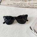 Close-up of black cat-eye sunglasses with unique scalloped wavy texture on the frame - Black and Gray