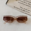 Detail einer Cat-Eye-Sonnenbrille mit teefarbenem Rahmen und Perlenverzierung oben - Champagner