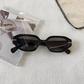 Detail of chunky black geometric sunglasses featuring silver metal accents on a textured surface - Black Frame Grey Lens