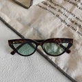 Detailed view of tortoiseshell cat-eye sunglasses on artistic textured fabric background - Dark Tortoise Frame Light Green Lens