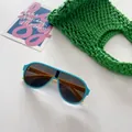 Détail de lunettes de soleil aviateur bleues et jaunes pour enfants sur fond vert - Gris Bleu