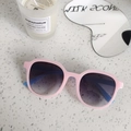 Close-up of pink matte frame sunglasses with blue arms on textured stone surface - Pink Blue Patchwork Plaid