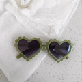 Close-up of heart-shaped sunglasses with scalloped green glitter frame and tinted lenses - Pixel Green