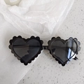 Close-up of heart-shaped sunglasses with wavy edges and black glossy frames on marble - Metal Leg Black