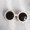 Cute sunflower shaped kids sunglasses with cream frames and dark lenses on stone base - Beige