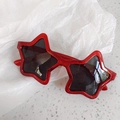 Detailed view of red glitter star-shaped children sunglasses with dark UV lenses - Red