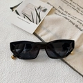 Detailed macro view of black cat-eye sunglasses with geometric frame and gold metal hinges - Black and Gray