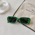 Close-up of green rectangular retro sunglasses on white textured surface with decor - Green