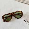 Detalle de gafas de sol extragrandes de leopardo con cristales verde claro en fondo blanco - Carey Lente Verde