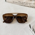 Detail of vintage brown sunglasses with a double-bridge frame on a textured background - Transparent Dark Tea