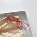 Kids square photochromic anti-blue light glasses in translucent pink frame on paper - Pink Photochromic