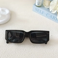 Detailansicht einer schwarzen rechteckigen Sonnenbrille auf einem Deko-Hintergrund - Dunkelgrau