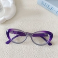 Occhiali da sole cat-eye con lenti viola sfumate su un tavolo bianco in stile minimalista - Viola Sfumato (Lente Bianca)
