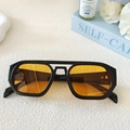 Détail de lunettes de soleil vintage à double pont noires avec des verres ambrés élégants - Monture Noire Verres Jaunes