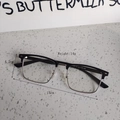 Detail view of half-rim glasses with black browline and silver frame on a stone table - Silver