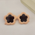 Macro view of peach flower-shaped kids sunglasses with matte frame and dark round lenses - Orange