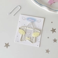 Detail eines sternförmigen Acryl-Kartenhalters mit Glitzer und Flügeln auf Dekohintergrund - Gelb