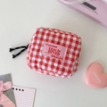 Detail of red checkered quilted cosmetic pouch with heart stitching and woven zipper pull - Red