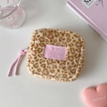 Detail of leopard print plush makeup bag featuring a pink brand label and soft faux fur texture - Yellow