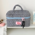 Close-up of black and white checkered heart-quilted makeup bag with pink zipper details - Black