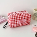 Détail d'une trousse à maquillage vichy rouge et blanc avec matelassage en cœur et zip - Rose rouge