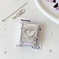 Macro shot of a silver mini album keychain with a heart window and cartoon dog print - Colorful Star
