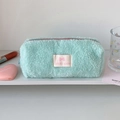 Gros plan d'une trousse en peluche vert menthe avec étiquette Lucky gate sur étagère - Vert Lac