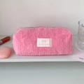 Détail d'une trousse rose en peluche avec fermeture éclair verte et étiquette Lucky gate - Rose Rouge
