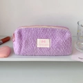 Détail d'une trousse à crayons violette en peluche douce avec écusson et fermeture rose - Violet