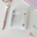 Macro detail of transparent PVC mini photo album with metal binder rings and snap closure - White Umbrella Shell