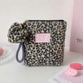 Detailansicht der Plüsch-Kosmetiktasche mit Leopardenmuster und flauschigem Anhänger - Schwarz