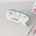 Trousse matelassée crème avec imprimé nœuds bleus et écusson sur un bureau - Nœud Bleu