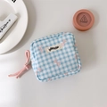 Detail of blue plaid makeup bag with pink bow pattern and zipper closure on a white desk - Blue Plaid